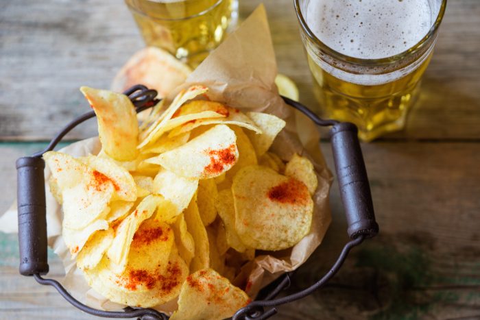 High Angle View Of Fresh Crunchy Potato Chips With Beer On Table