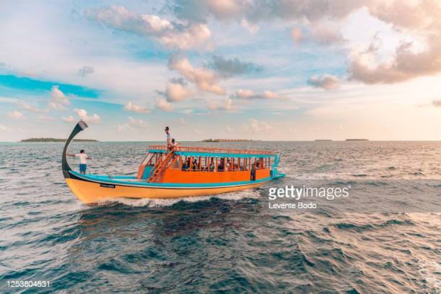 Wonderful Maldivian boat Dhoni on tropical blue sea, taking tourist to a sunset cruise.